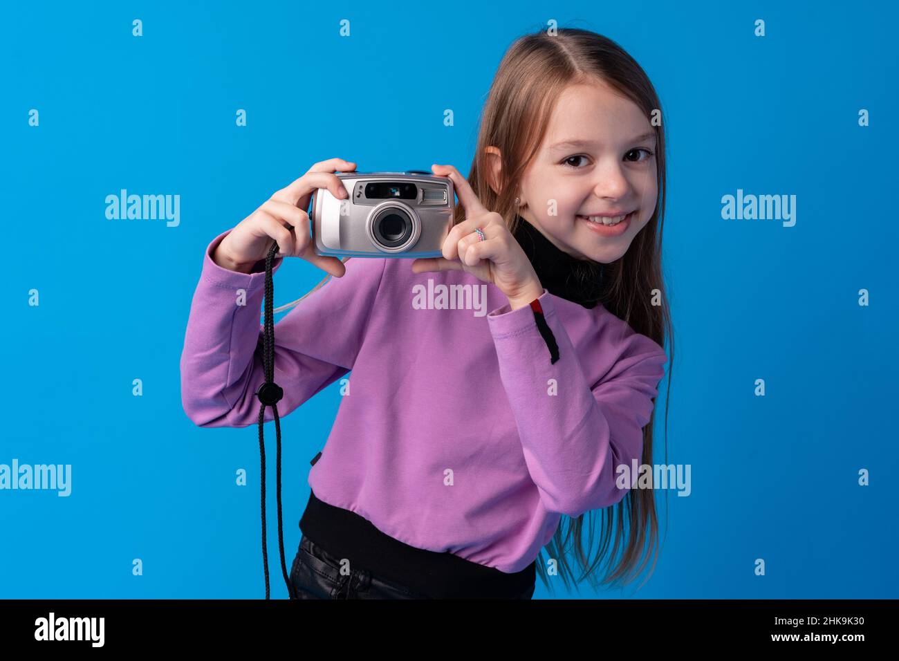 Portrait of a little girl with camera against blue background Stock ...