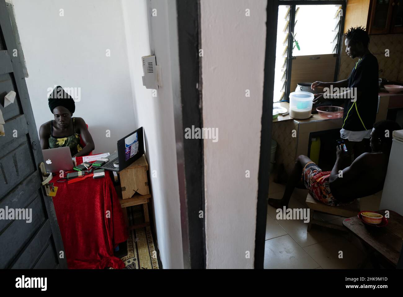 Va-Bene Elikem Fiatsi, 40, a trans woman who is an artist and LGBT+ activist, works inside her office as her studio assistant, Martin Toloku, 29, and brother, Wonder Fiatsi, prepare lunch in the next room, at their home and studio in Oduom, Ashanti Region-Ghana, December 23, 2021. 'There are many more of us that will be born, even far after I'm gone,' she said. 'What I do today is not for me, or even for those living today. It's for the future generation.' REUTERS/Francis Kokoroko        SEARCH 'KOKOROKO GHANA LGBT' FOR THIS STORY. SEARCH 'WIDER IMAGE' FOR ALL STORIES Stock Photo