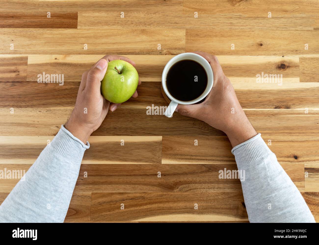 Top view photo of man holding coffee cup and apple. Concept of