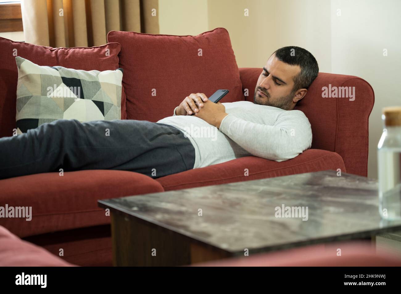 Close up photo of man suffering from narcolepsy sleeping on couch while holding smartphone. Stock Photo