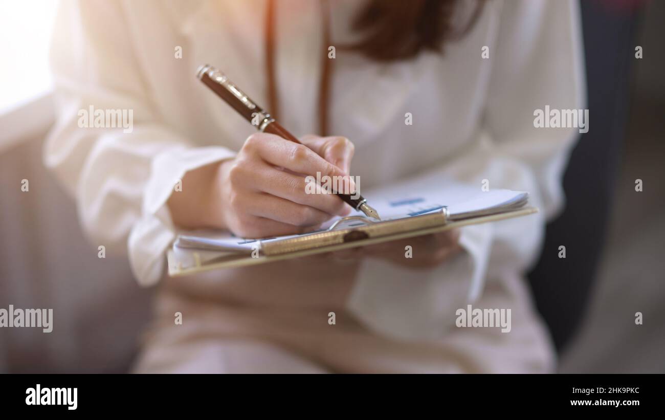 Close-up image, businesswoman or female entrepreneur signing her signature on a documents, approving the project. Stock Photo