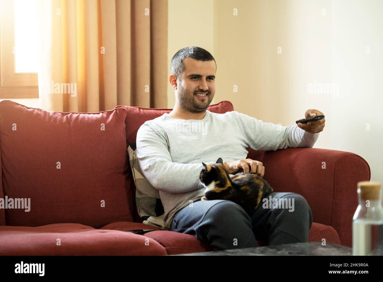 Close up photo of man holding tv remote control and relaxing with the cat. concept of tv watching. Stock Photo