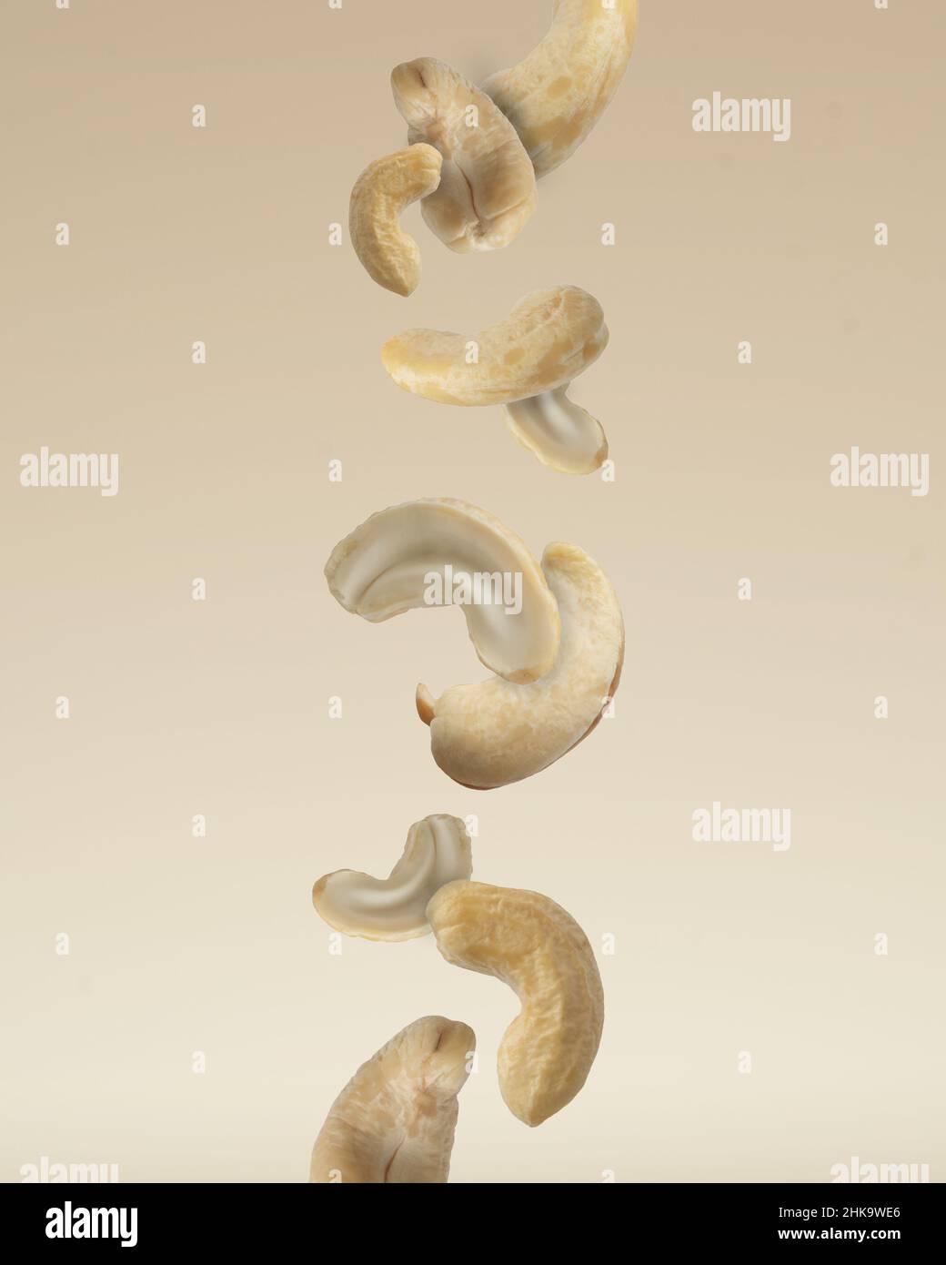 Close up photo of floating raw organic cashews on beige background. Stock Photo