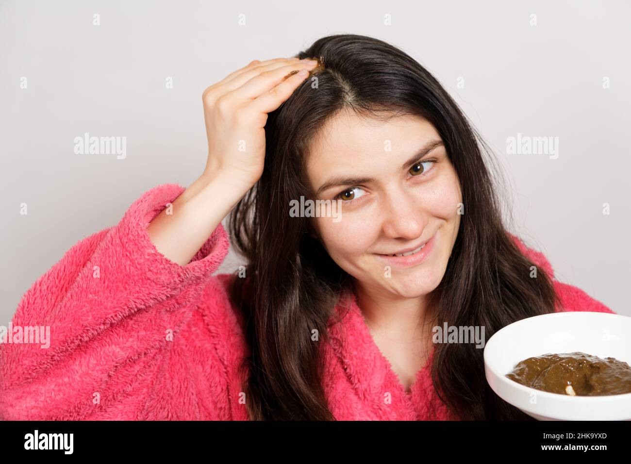 A brunette woman applies a natural Ayurvedic blend of herbs to her hair, scalp mask and scrub, hair care at home. Stock Photo