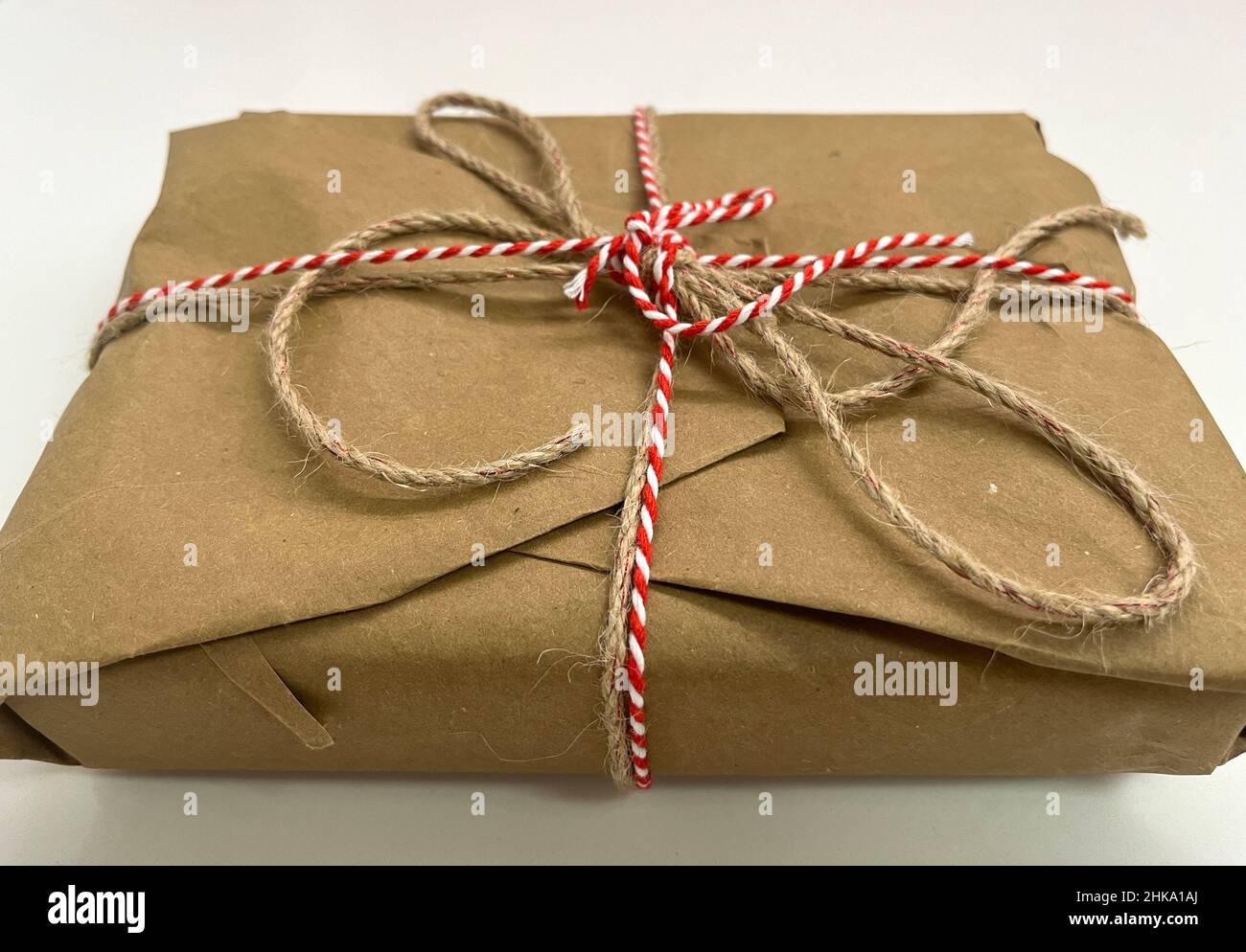 A gift wrapped in plain red paper with a raffia bow isolated on a white  background Stock Photo - Alamy