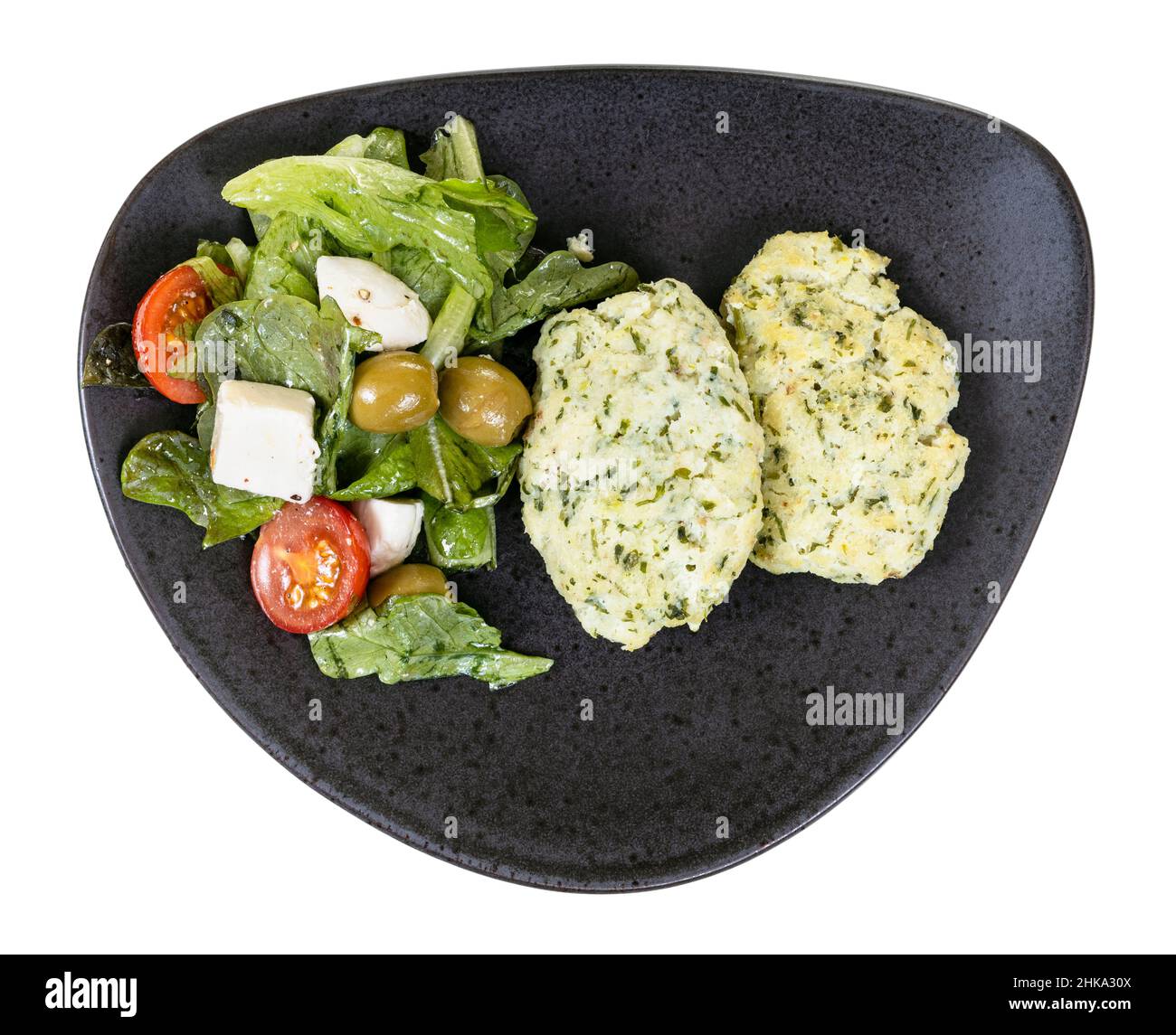 top view of steamed homemade minced cod fish balls with salad on black plate isolated on white background Stock Photo