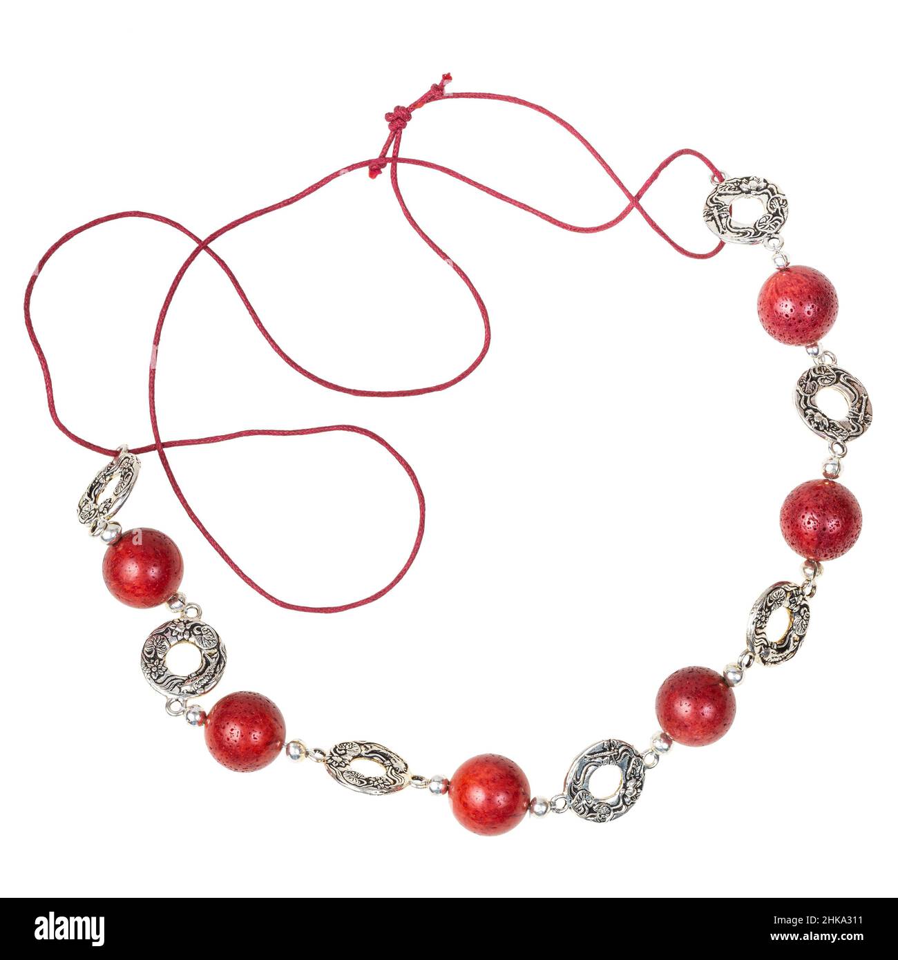 handcrafted necklace of polished red coral balls and decorated silver rings on red leather cord isolated on white backhround Stock Photo