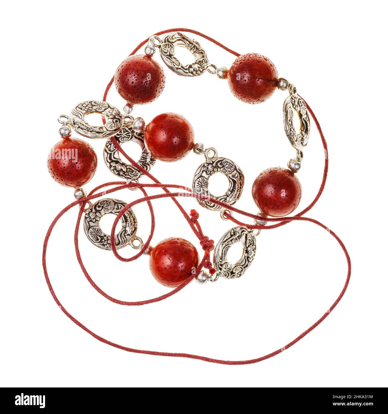 tangled handcrafted necklace of polished red coral balls and decorated silver rings on red leather cord isolated on white backhround Stock Photo