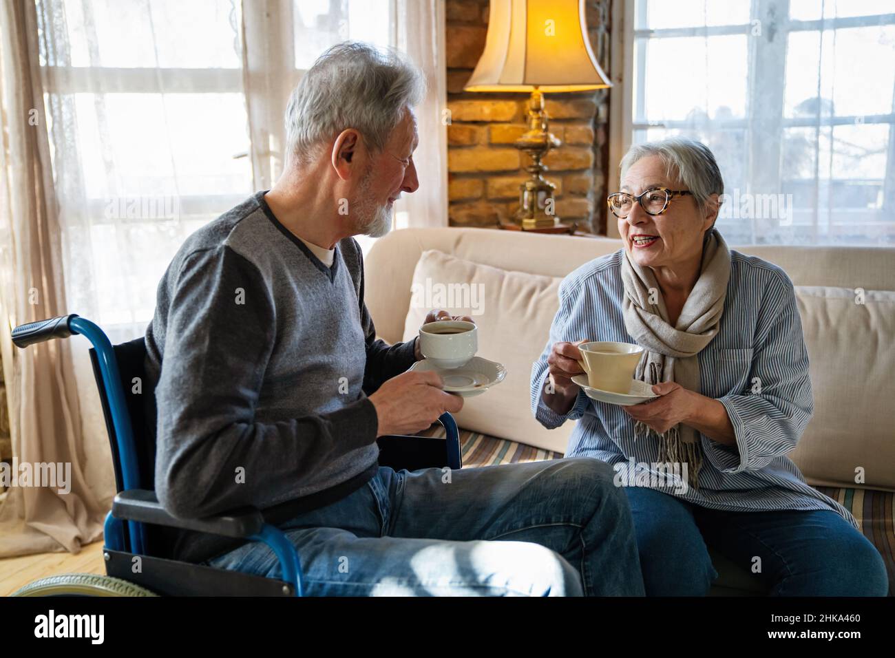 Mature man with disability in wheelchair. Happy retired senior couple having fun at home. Stock Photo