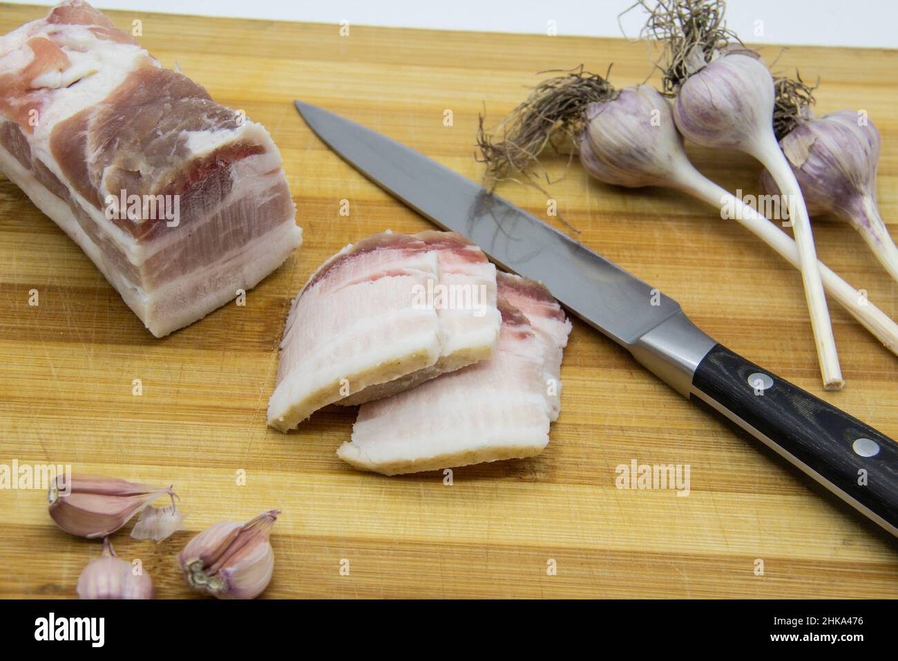 Ukrainian products raw lard with peppercorn and garlic, knife, slices of salo being on cutting board. Ukrainian traditional food concept. Stock Photo