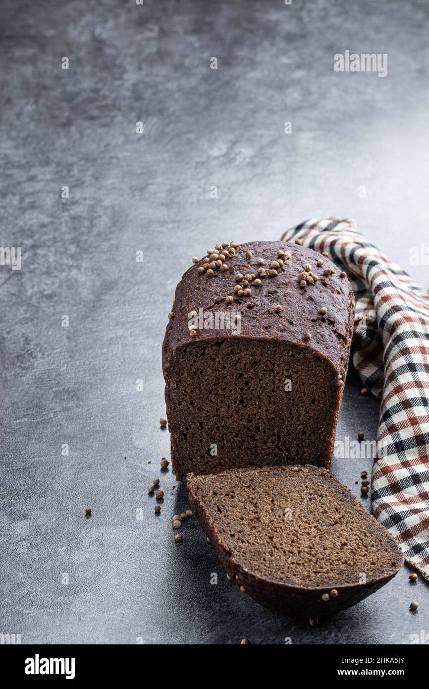 Homemade dark rye bread with coriander seeds on gray stone background