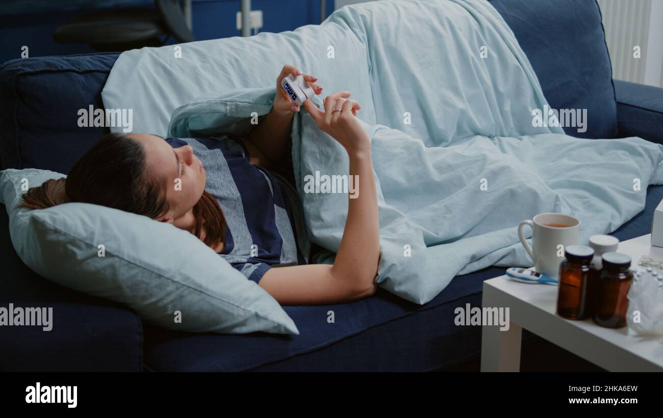 Sick person with fever using oximeter to measure pulse pressure and