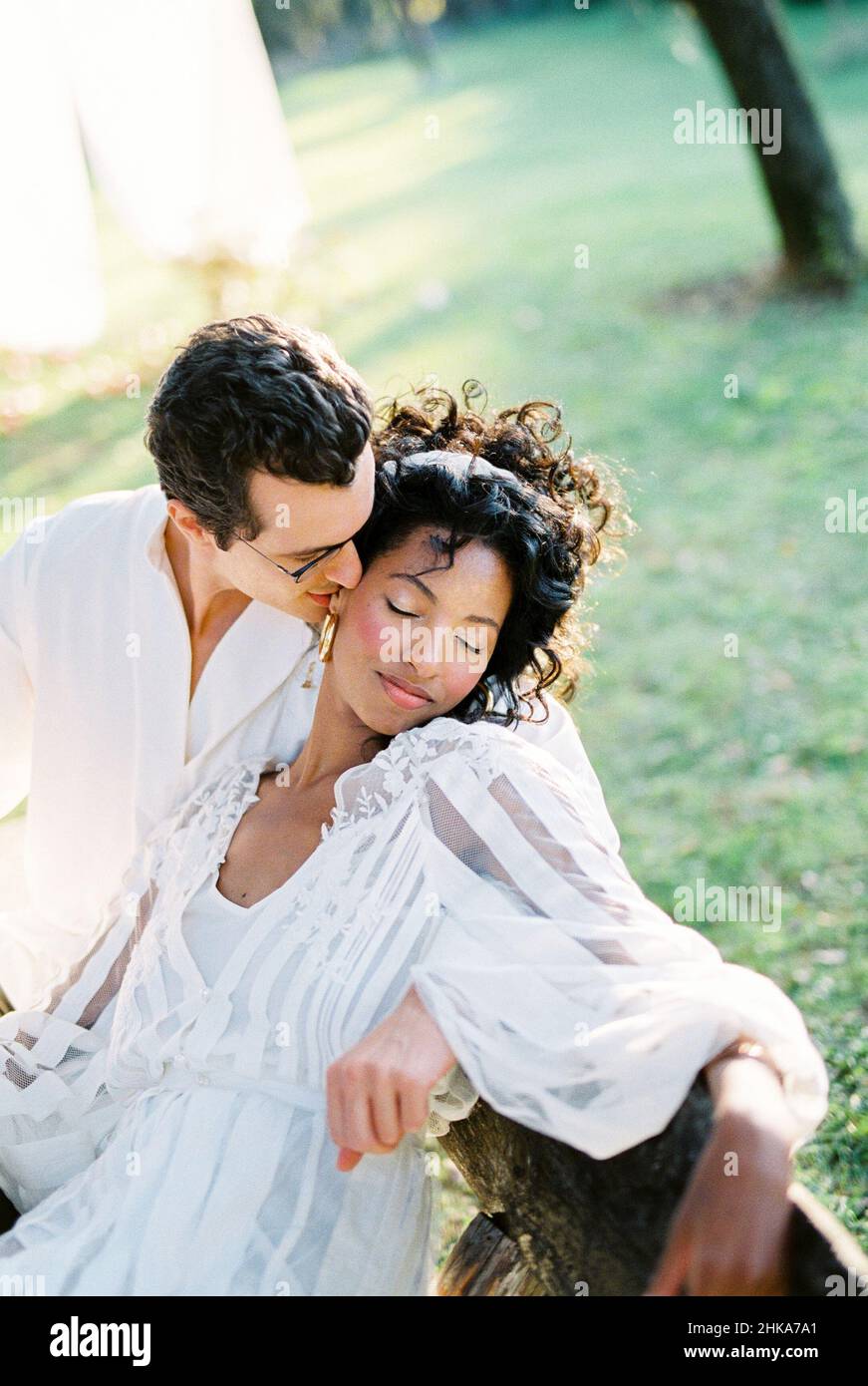 Man hugs and kisses a woman sitting on a bench Stock Photo - Alamy
