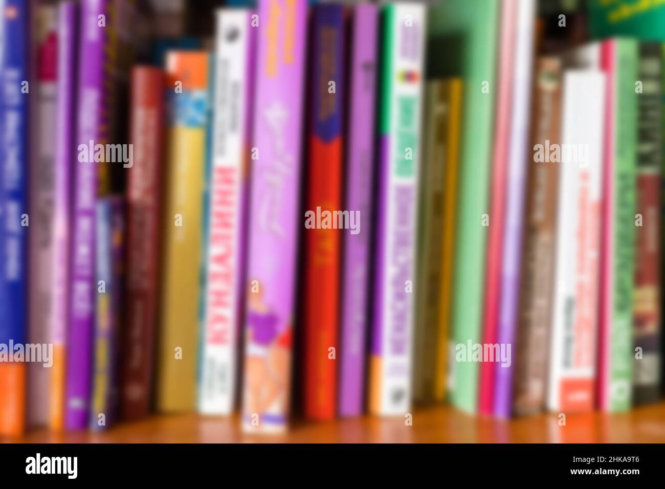 Multi colored books on bookshelf blurred background. Home library reading books concept. Close-up. Stock Photo