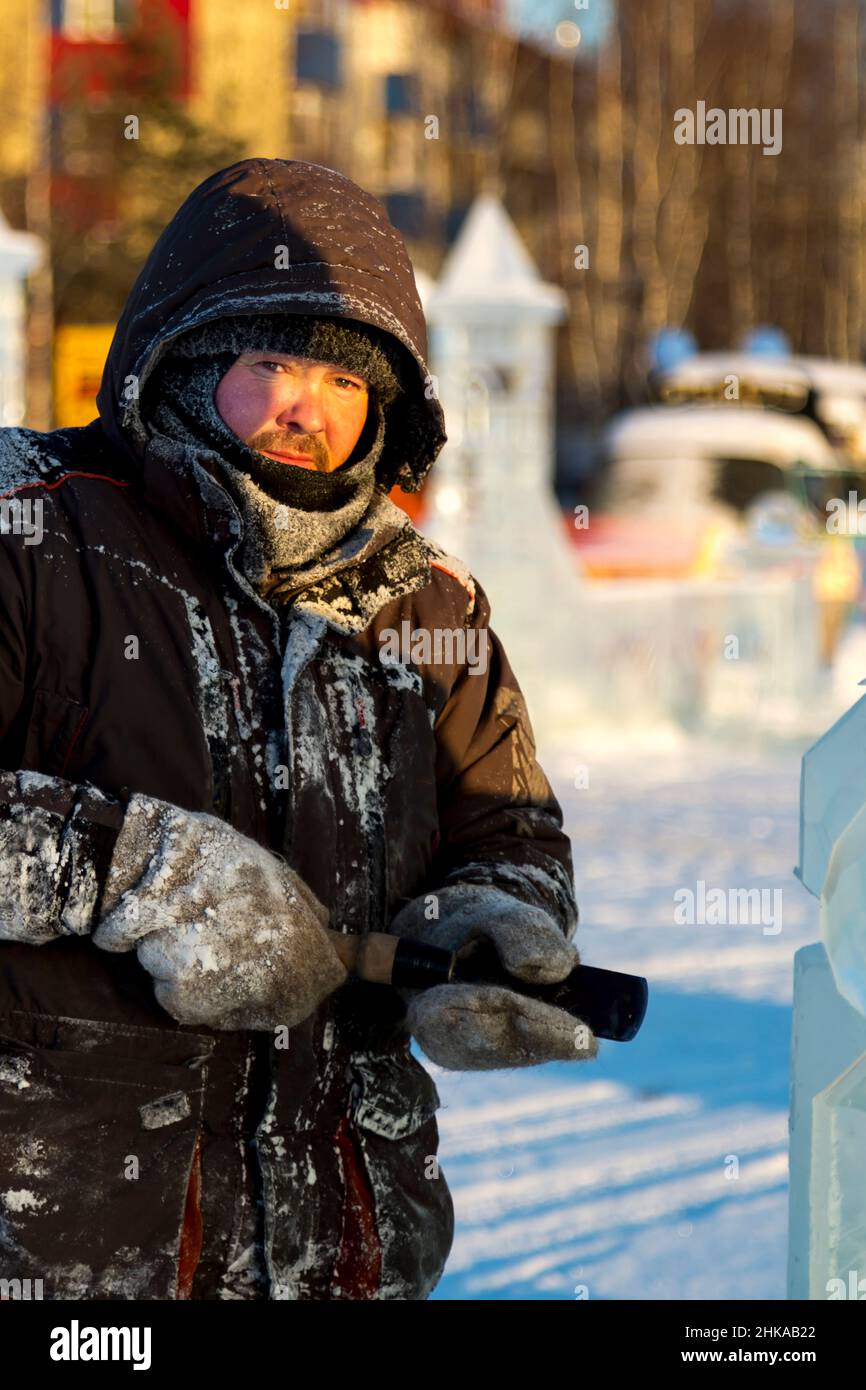 The sculptor cuts an ice figure out of an ice block with a chisel Stock ...