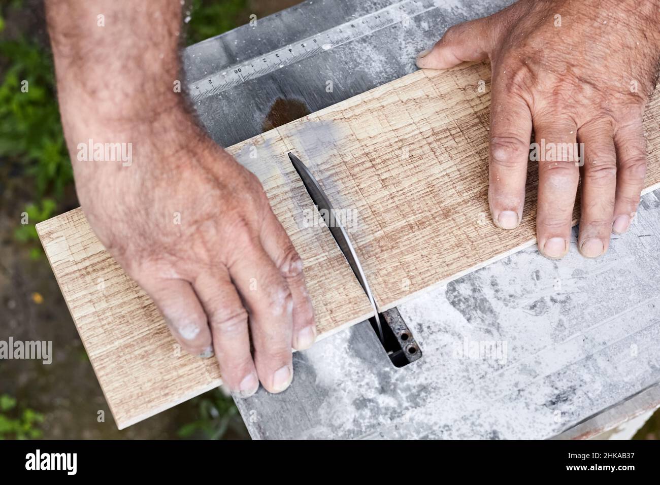 A man cuts a ceramic tile using a tile cutter with water cooled. Close-up, selective focus Stock Photo