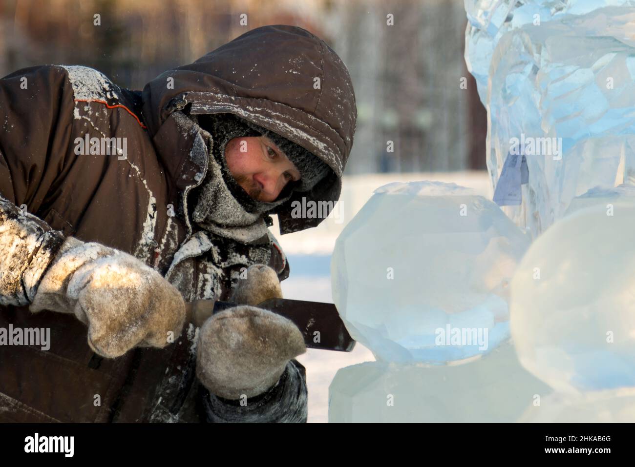 The sculptor cuts an ice figure out of an ice block with a chisel Stock ...