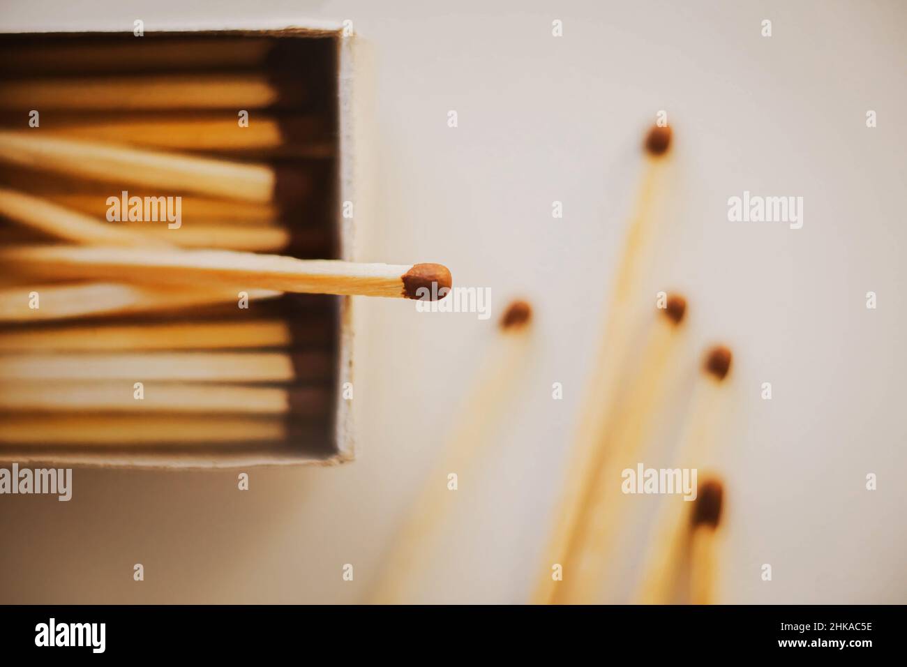 On a white table there is an open cardboard box with wooden matches, and next to it are five matches pulled out. Flammable items. Household items. Stock Photo