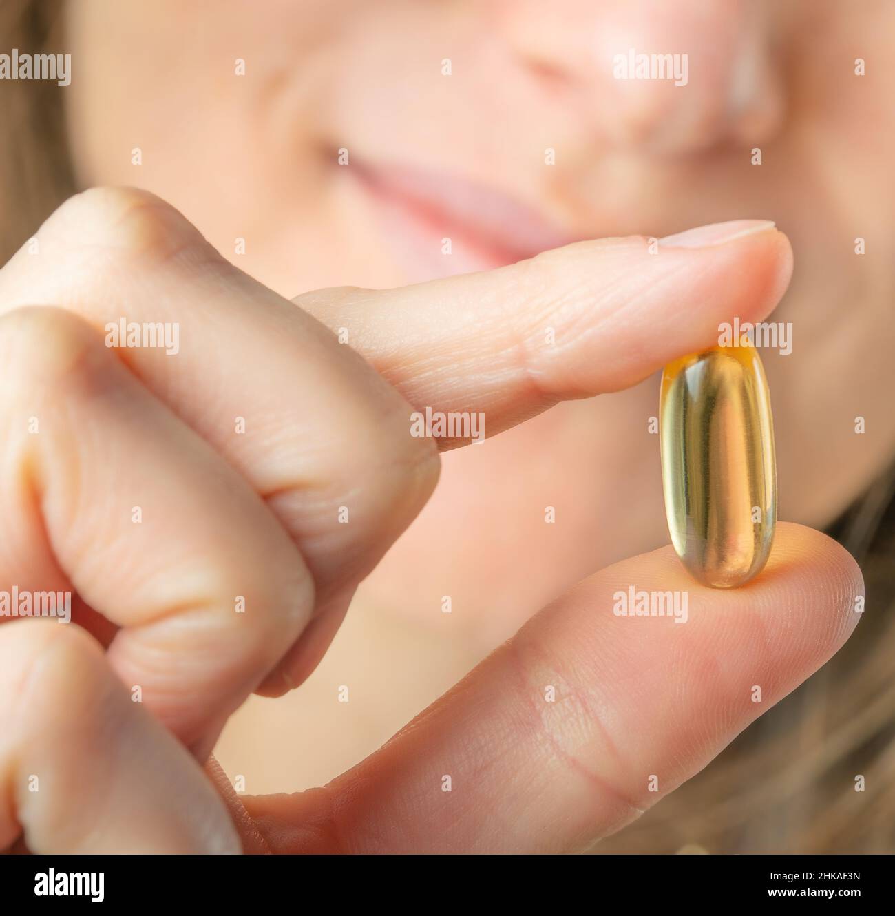 Female holding Omega 3 soft gel capsule in hand. Close up, selective focus. Stock Photo