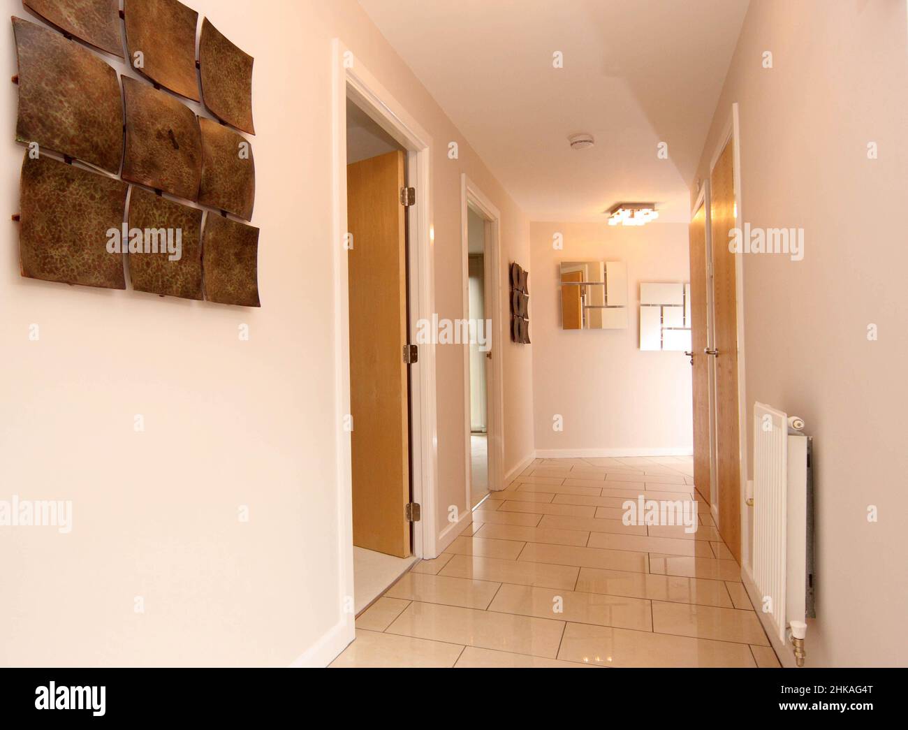 View along a corridor passageway with tiled floor in modern house property,doors off to other room, modern aspect. Stock Photo