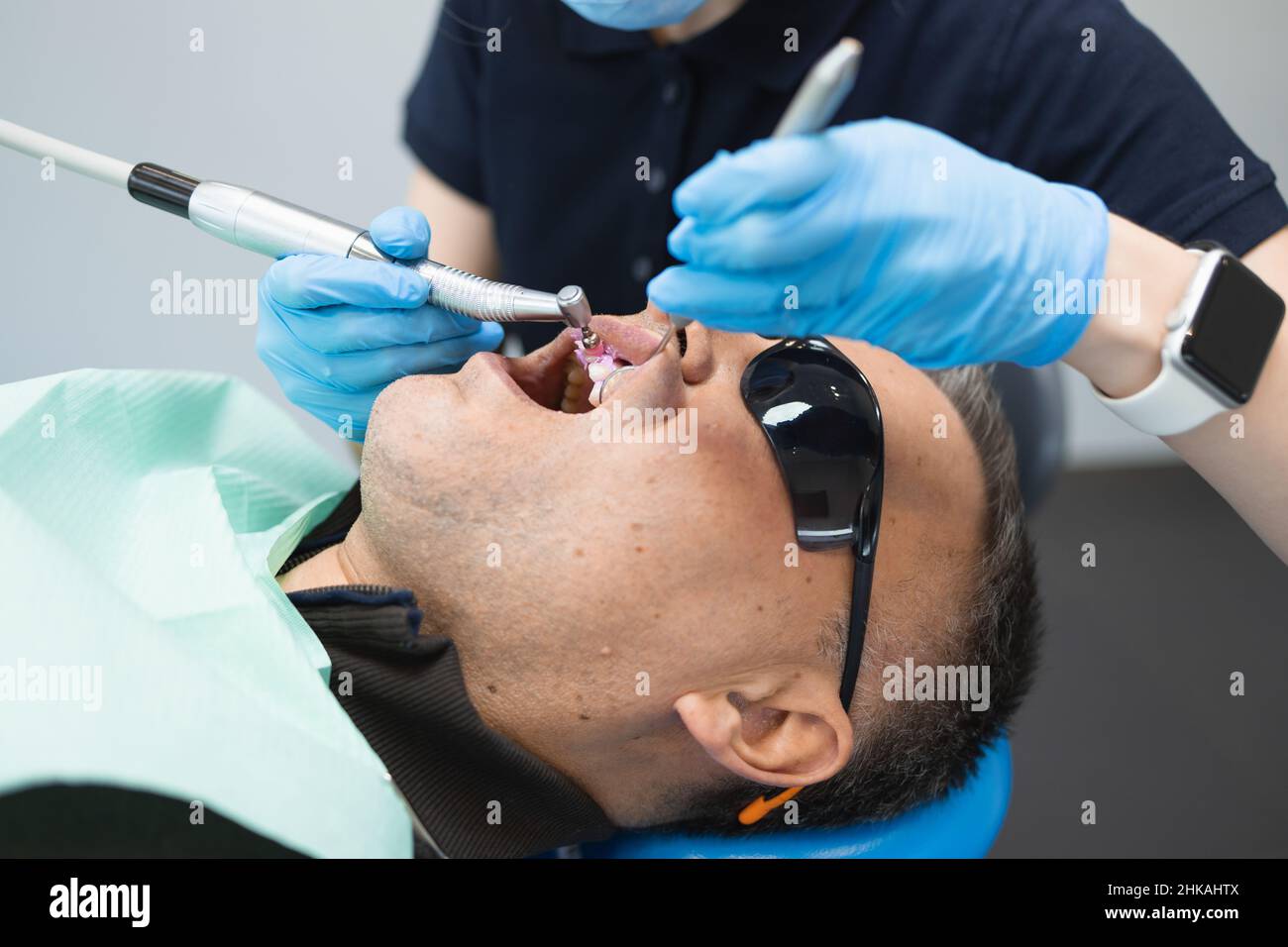Dentist doing teeth cleaning procedure for male patient. Professional