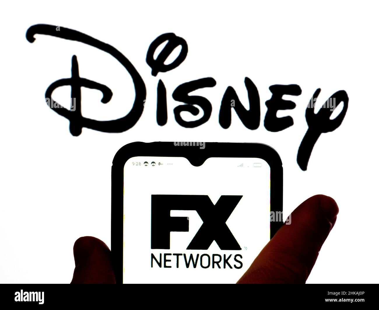 In this photo illustration, the FX Networks logo is displayed on a  smartphone screen with a Disney logo in the background Stock Photo - Alamy