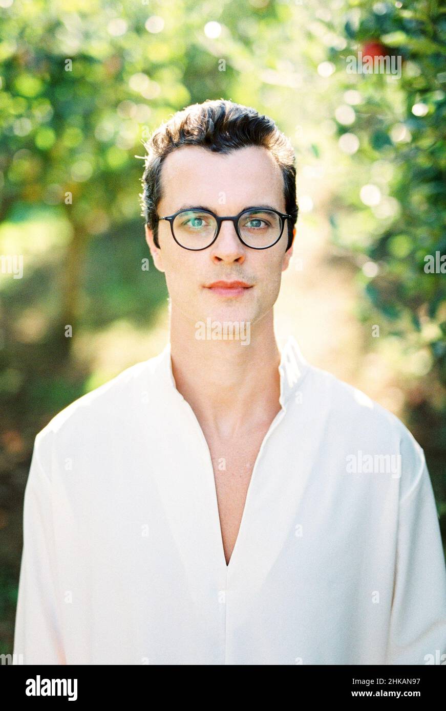 Portrait of a man in a white shirt and glasses on a background of green ...