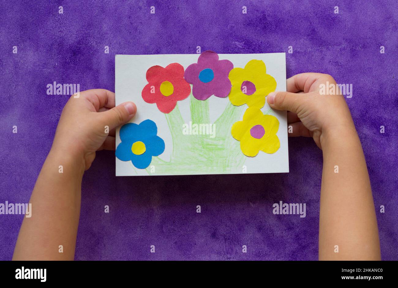 Handmade greeting card with flowers in child hands on the purple ...