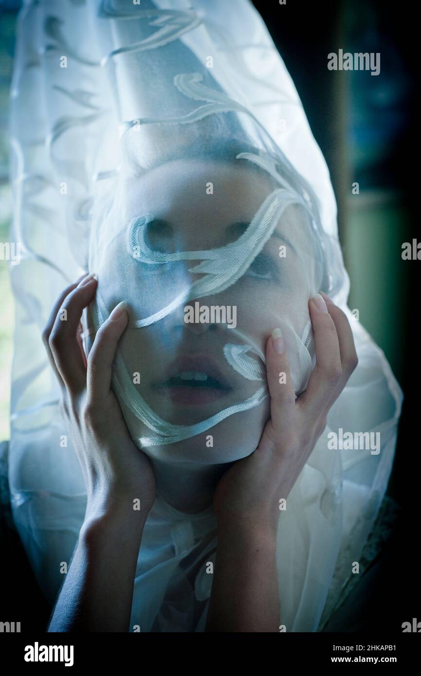 Womans face wrapped in transparent patterned curtain Stock Photo - Alamy