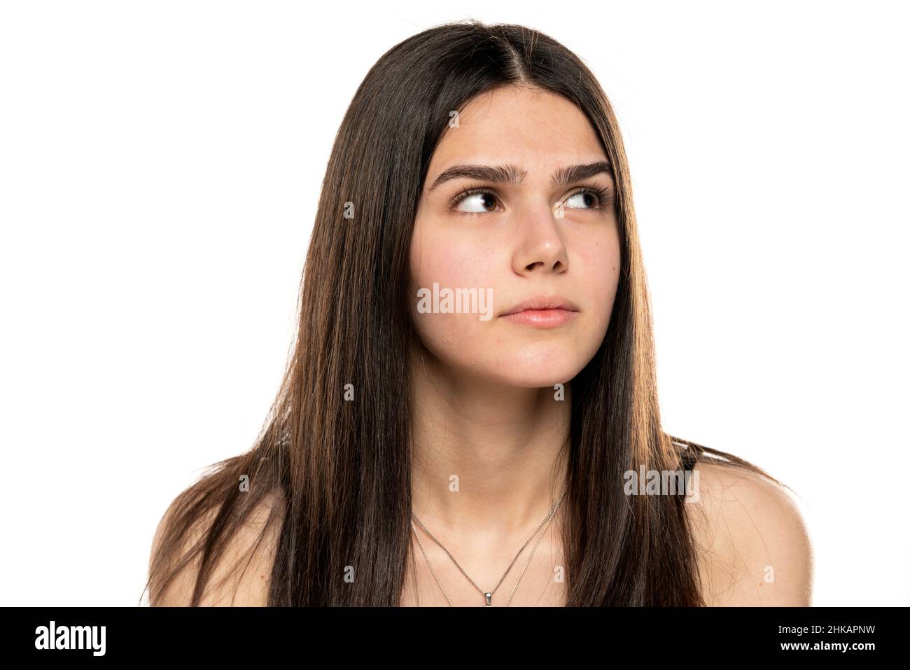 a young teenager girl looks away and thinks against a white background Stock Photo