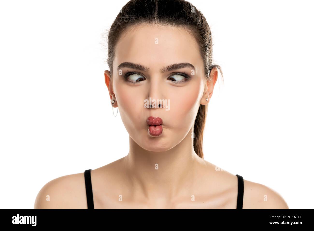 portrait of a funny teen girl with crossed eyes and a fish face on a