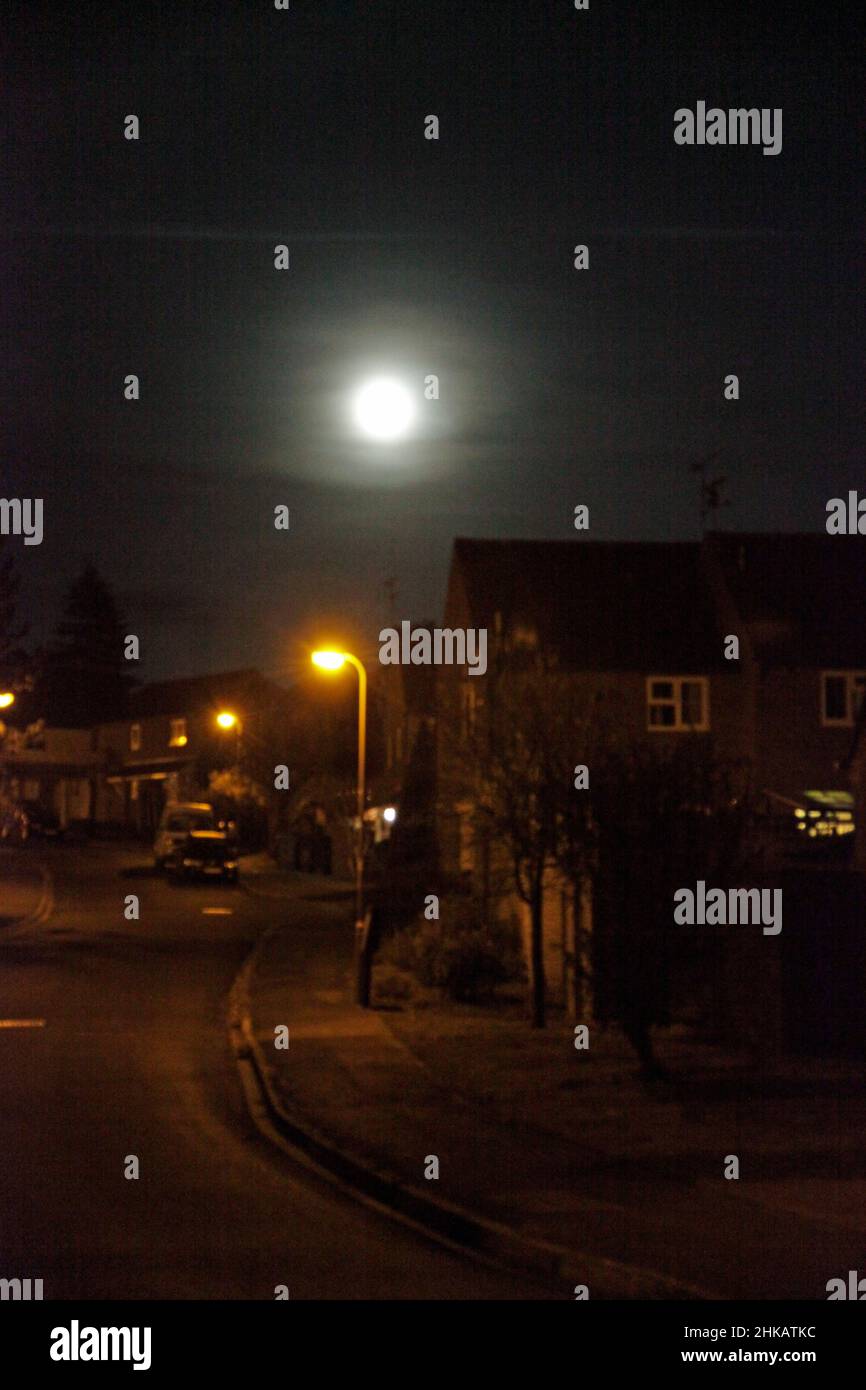 A hazy moon shines down onto an English street on a dark, winter's evening Stock Photo