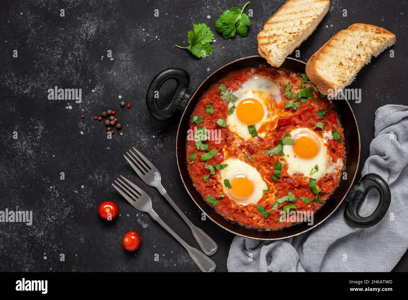 Shakshuka eggs in a pan with toast on a black concrete background