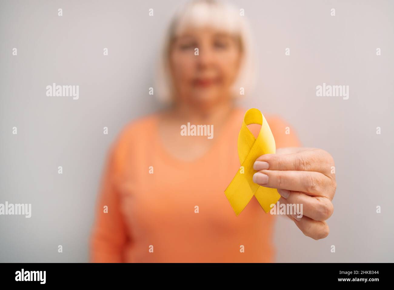 woman hand holding yellow ribbon symbol of Childhood cancer Awareness