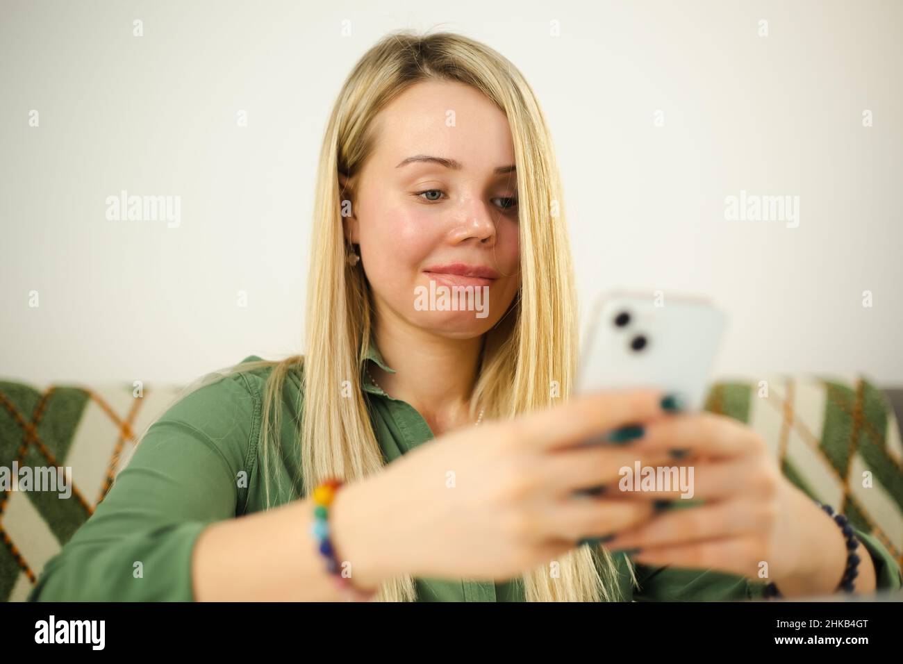 Domestic violence victim with facial scar and prosthetic eye typing message on modern mobile phone with cheerful smile. Abuse survivor woman living ha Stock Photo