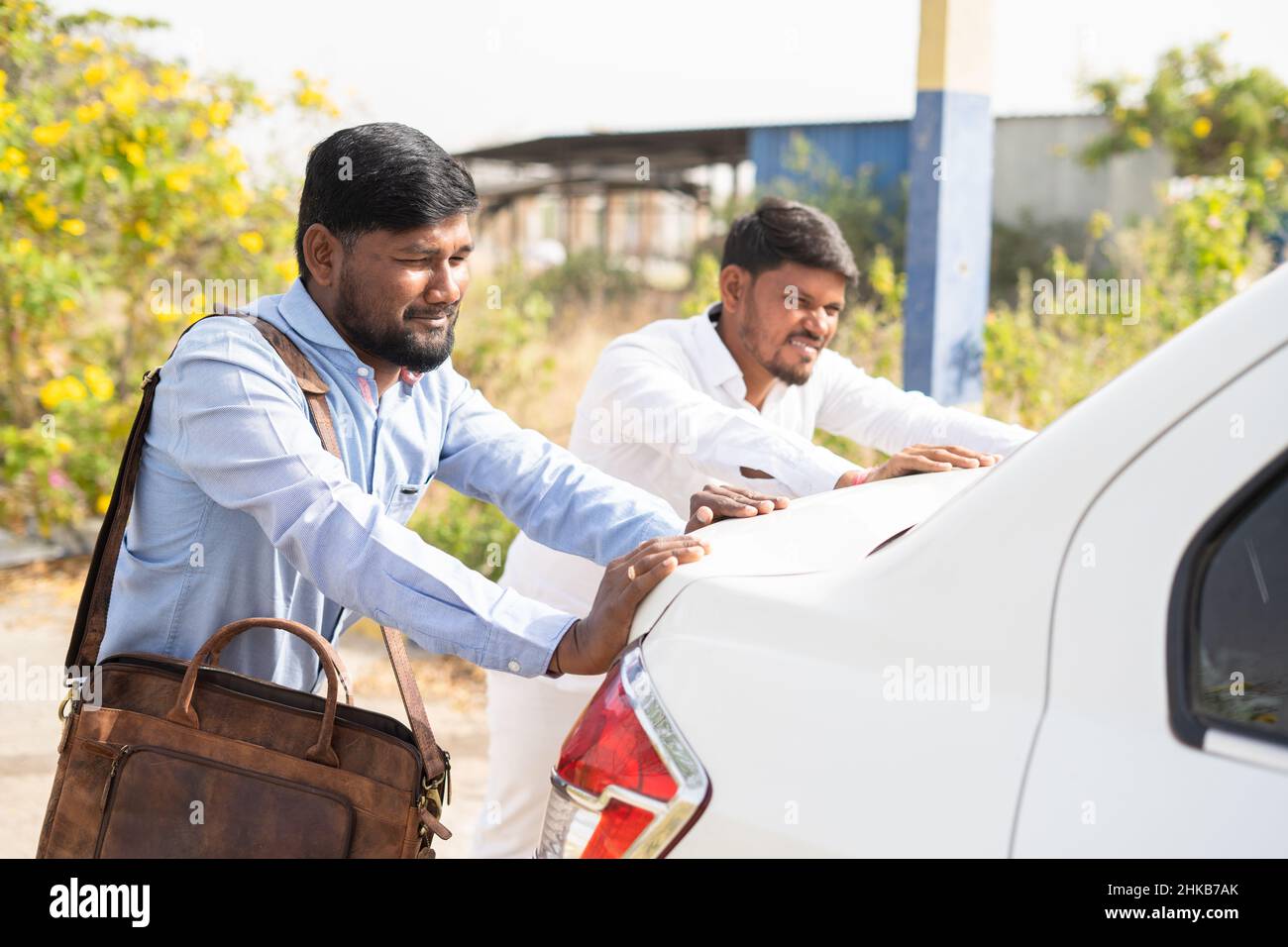 Side view shot of Worried cab driver and passanger pushing the car on roadside - concept of car breakdown, journey, helping hand and transportation Stock Photo
