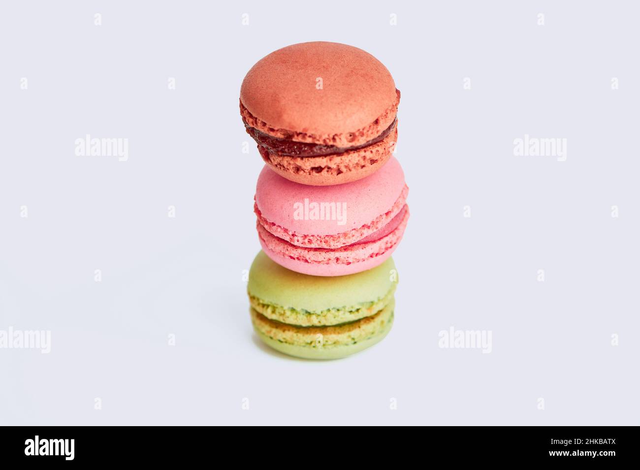 three macaroons in brown, pink and green against white background Stock Photo