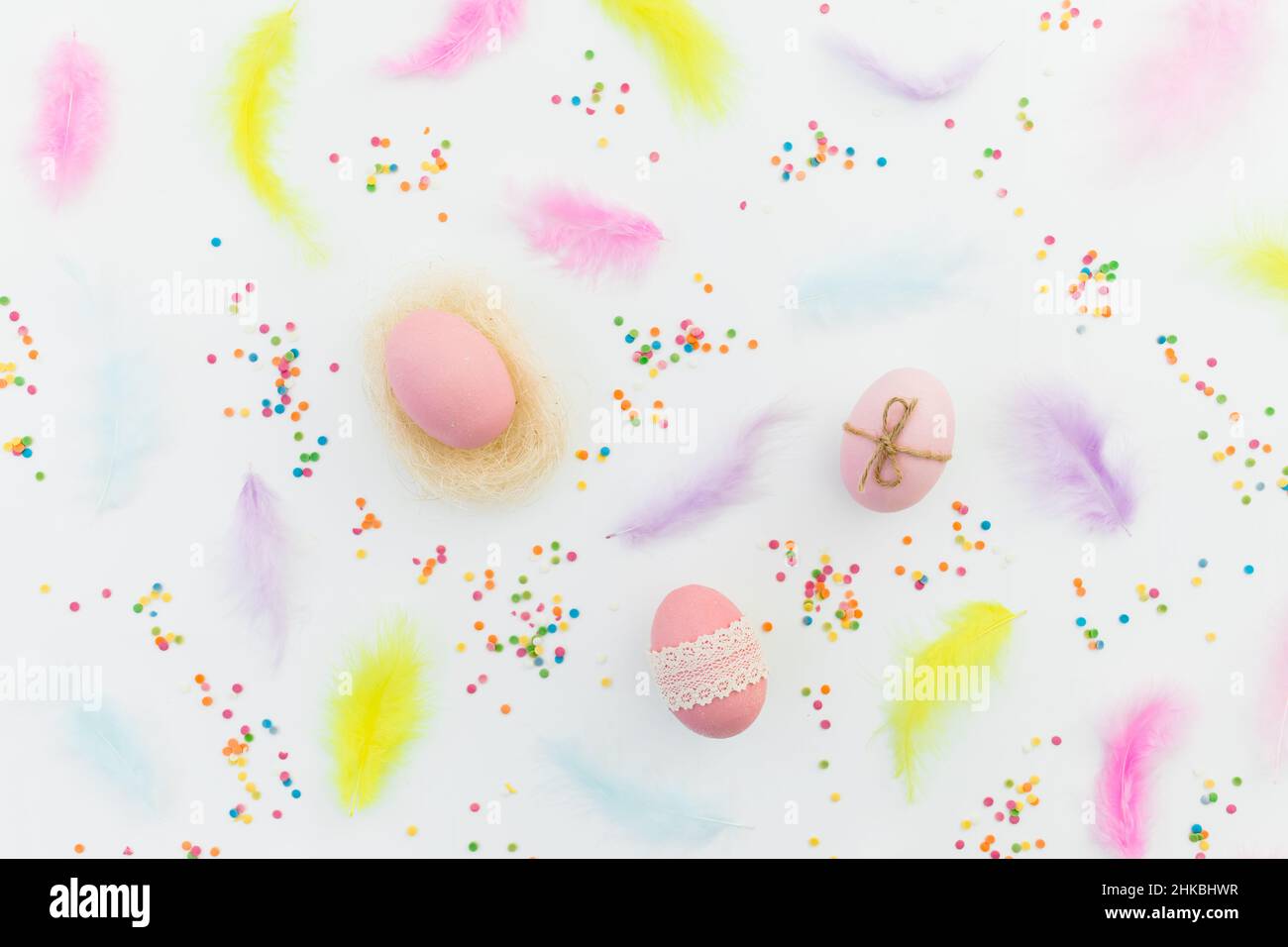 Ester composition with eggs, feathers and confetti on white background. Flat lay, top view Stock Photo