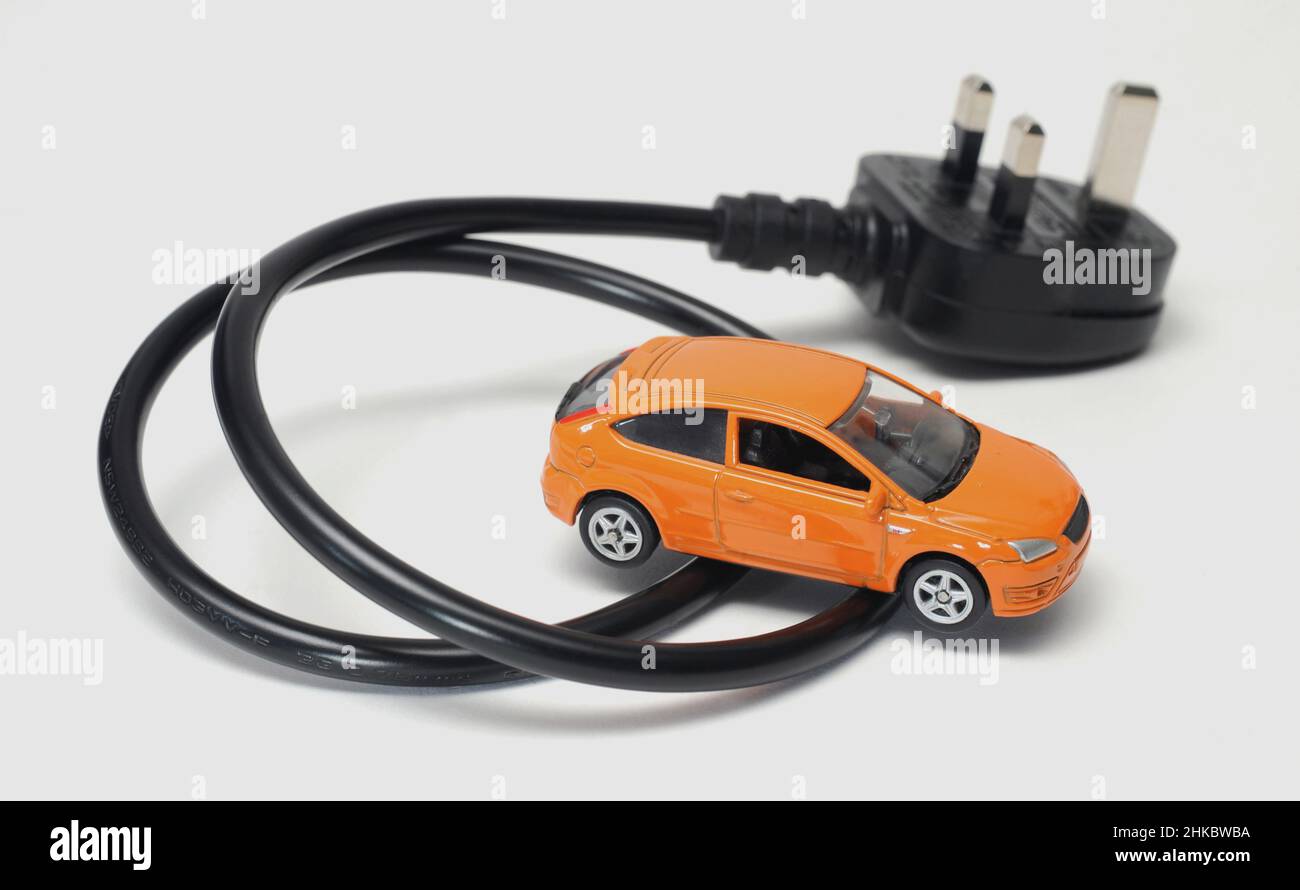 MODEL CAR WITH ELECTRIC PLUG AND LEAD RE EV'S EV ELECTRIC CAR DIESEL PETROL FUEL THE ENVIRONMENT BATTERY CARS ETC UK Stock Photo