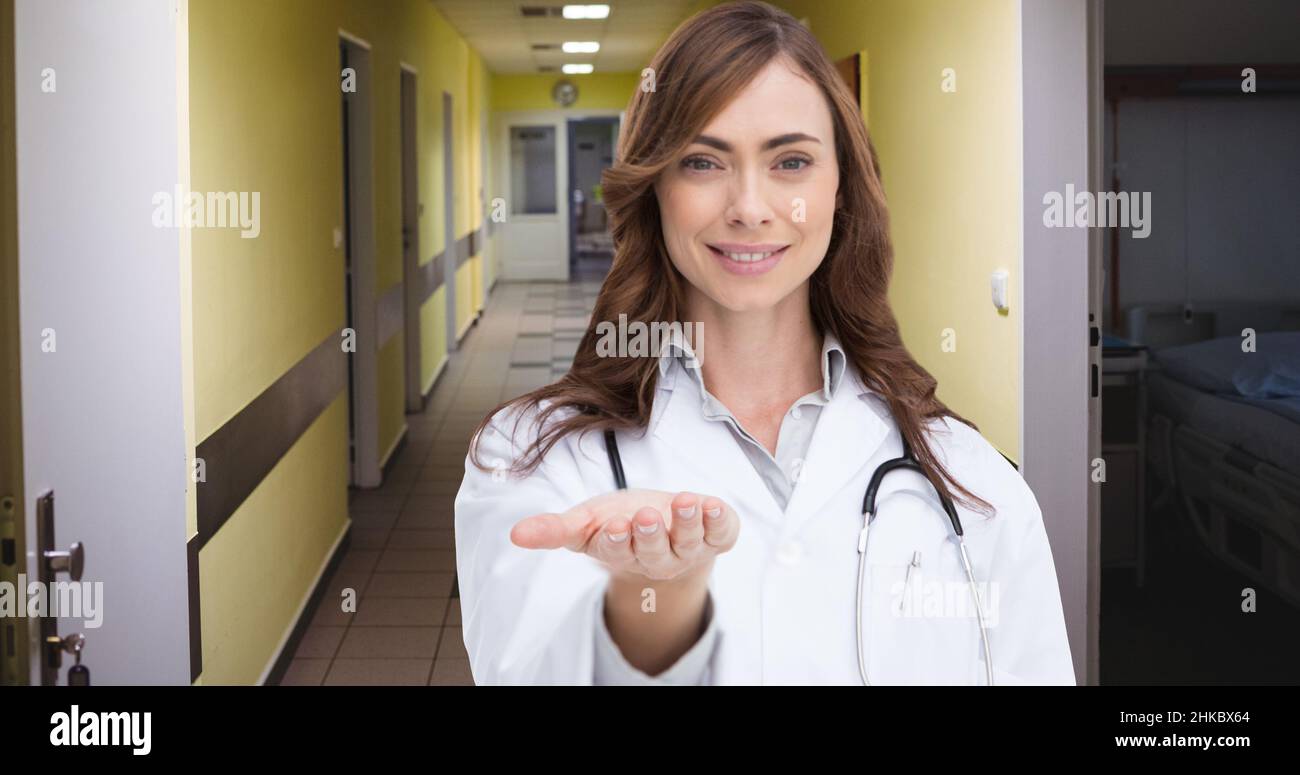 Portrait of smiling mid adult caucasian female doctor gesturing while standing in hospital corridor Stock Photo