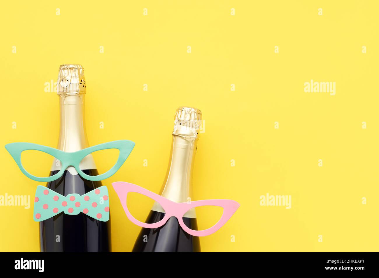 Holiday background with party props, masks, and champagne on a bright yellow background. Carnival concept. Top view, copy space Stock Photo