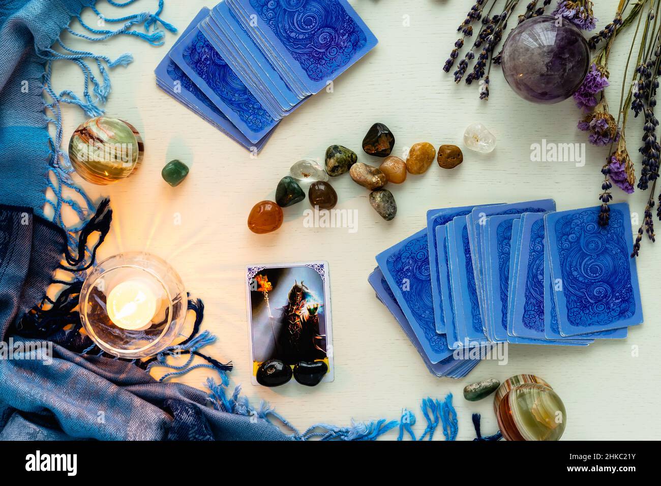 Minsk, Belarus - February 2022: Devil cards in tarot divination with candles and stones on a light table with dried flowers and a blue tablecloth. Mag Stock Photo