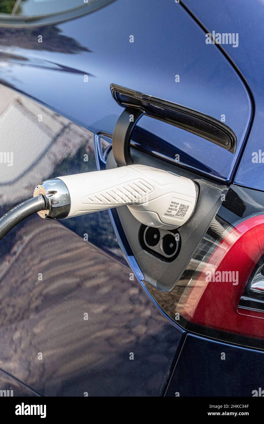 A charging power lead cable plugged in to a Tesla car Stock Photo