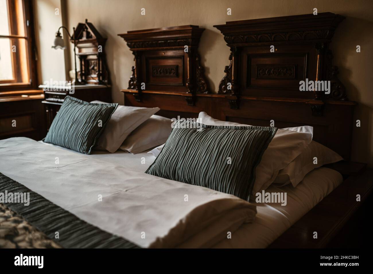 Stylish medieval antique European hotel bed with green pillows, sheets,  blanked, bedspread and room lamp at the background Stock Photo - Alamy