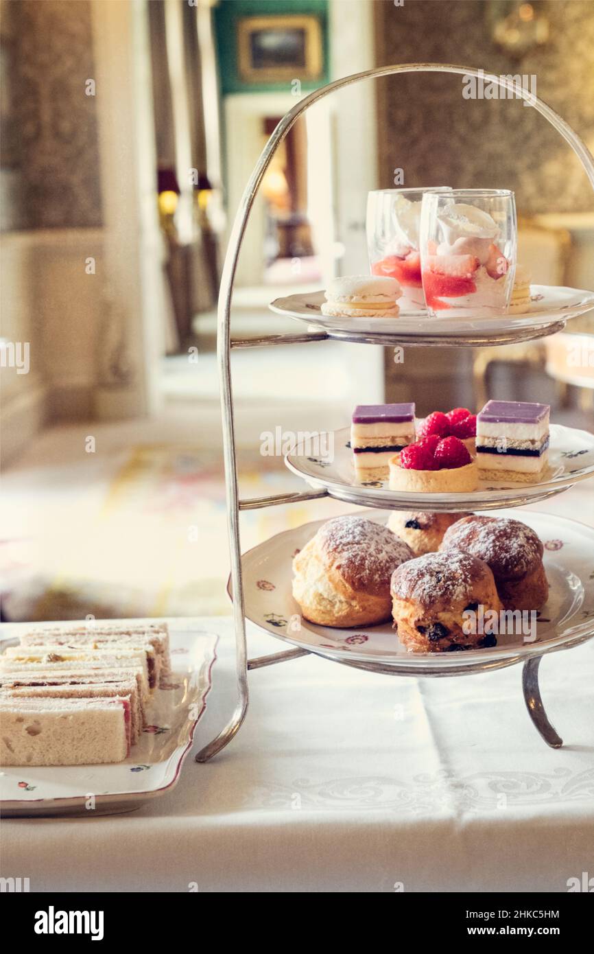 A cake stand full of very delicious sandwiches and fine cakes for an afternoon tea in an English stately home. Stock Photo