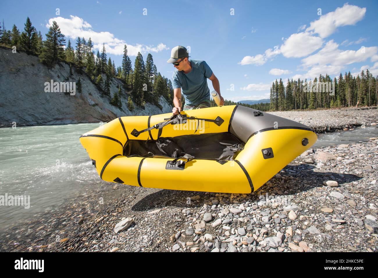 Adventurous man places packraft in river. Stock Photo
