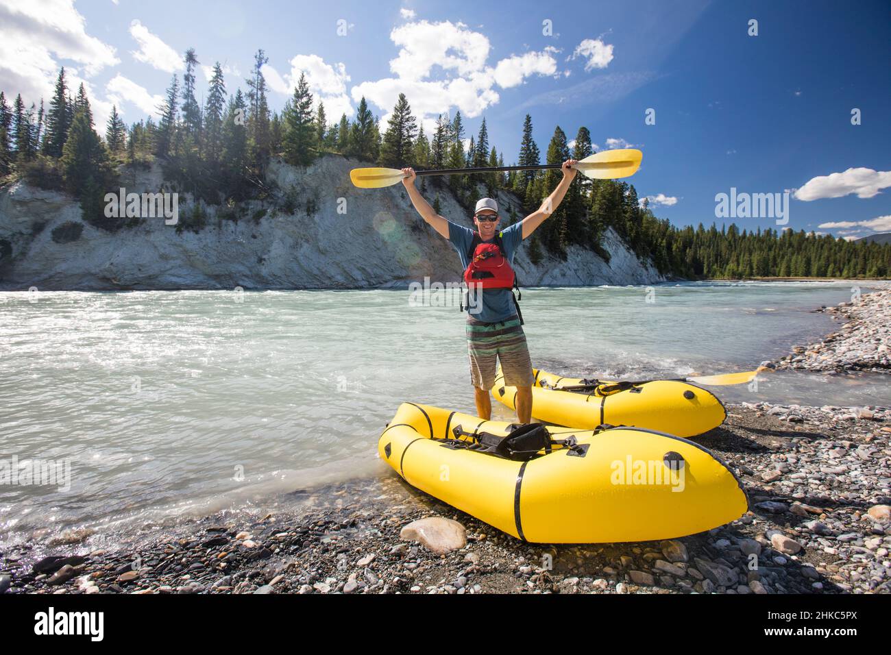 Paddler holds yellow paddle above head while rafting Stock Photo