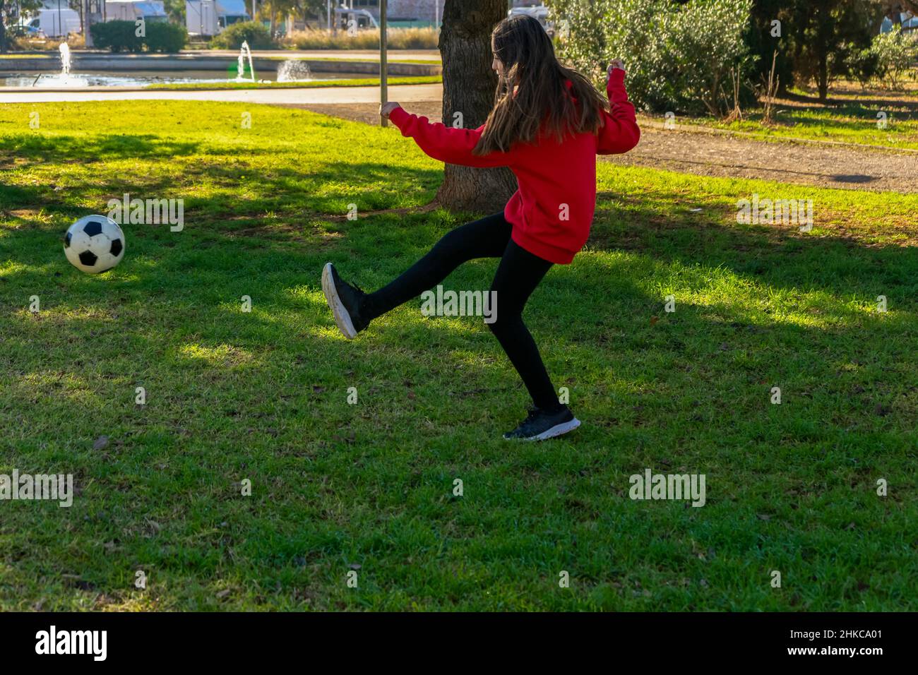 Beautiful little girl playing soccer in a nice park with natural grass ...