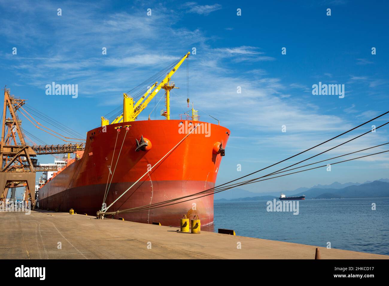 Red bulk carrier cargo ship loaded with soy at sea port on sunny summer day. Concept of logistics, commerce, economy, industry, transport, vessel. Stock Photo