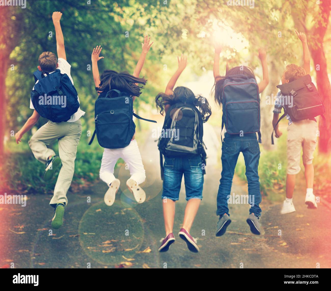 Spring break. Rearview shot of a group of school children jumping in the air. Stock Photo